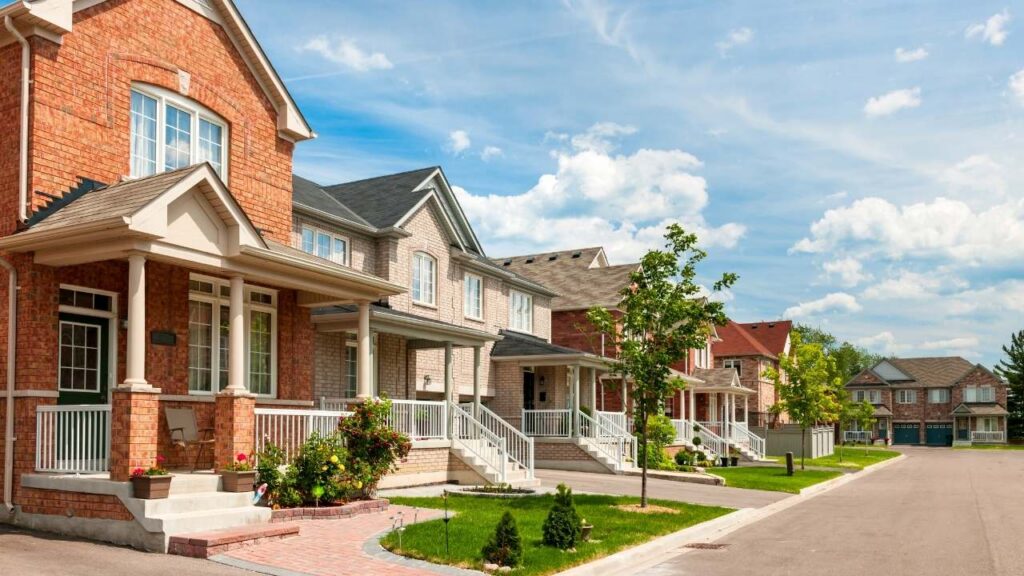 A row of newly constructed two-story suburban townhomes with brick and siding facades.