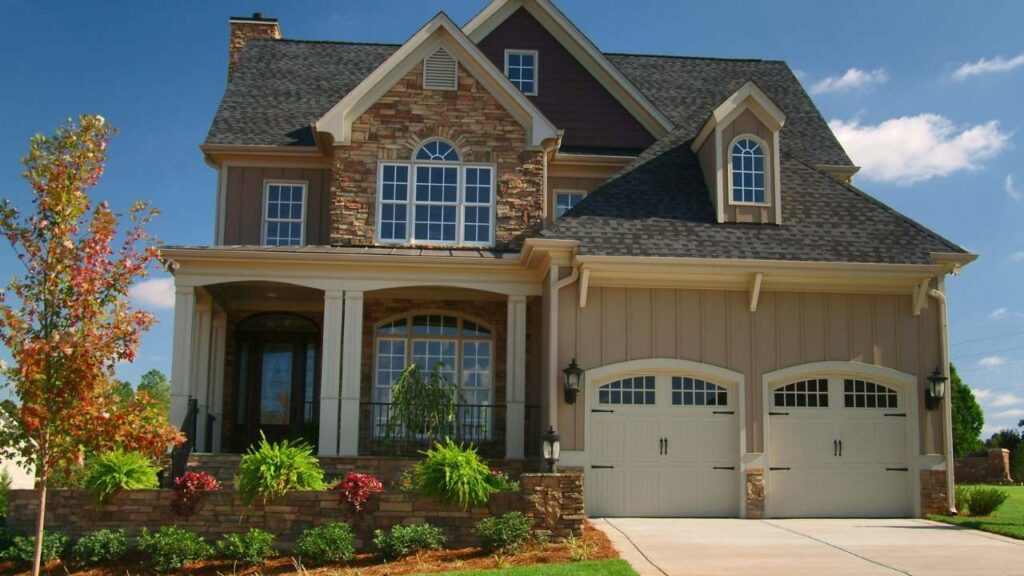 Traditional two-story brick and stone home with arched windows and beautifully manicured bushes.