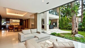 Elegant covered outdoor patio area with modern minimalist white seating and manicured landscape views.
