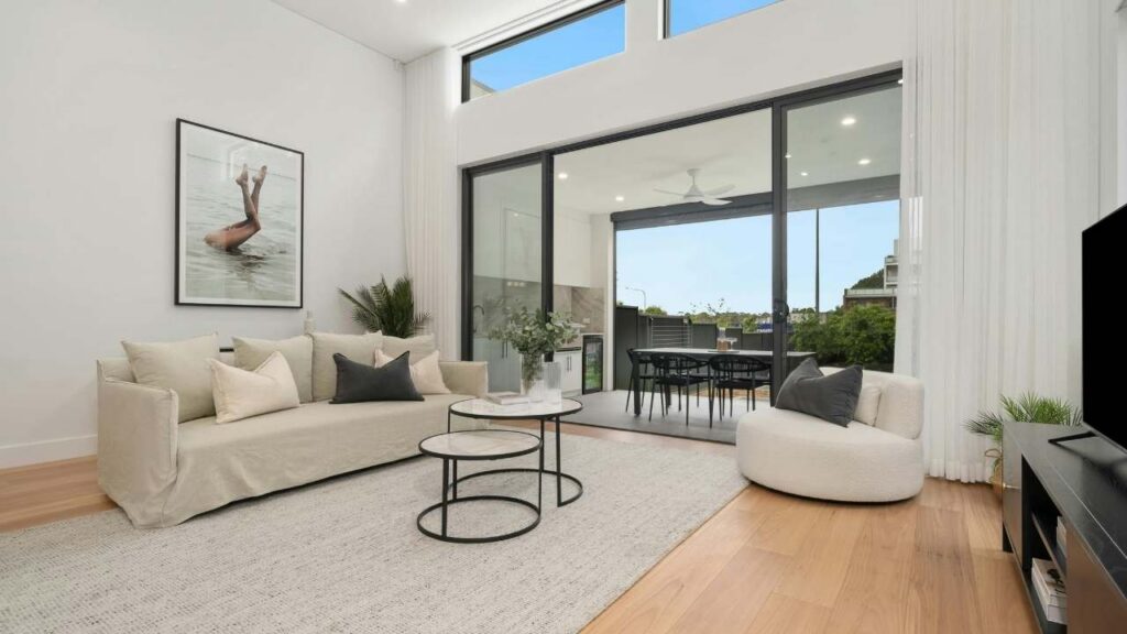 Modern open-concept living room with large sliding glass doors opening to a scenic backyard patio.