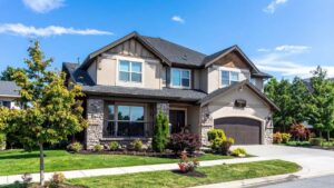 Modern two-story dark grey siding home with large rectangular windows and a lush green front lawn.