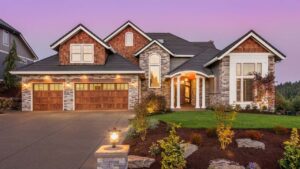 Large luxury two-story brick home illuminated by warm accent lighting at twilight.