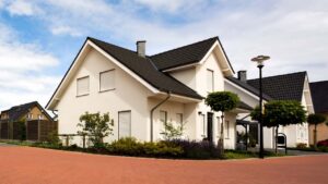 Minimalist white stucco two-story house with dark grey trim, dark roof, and manicured grass.